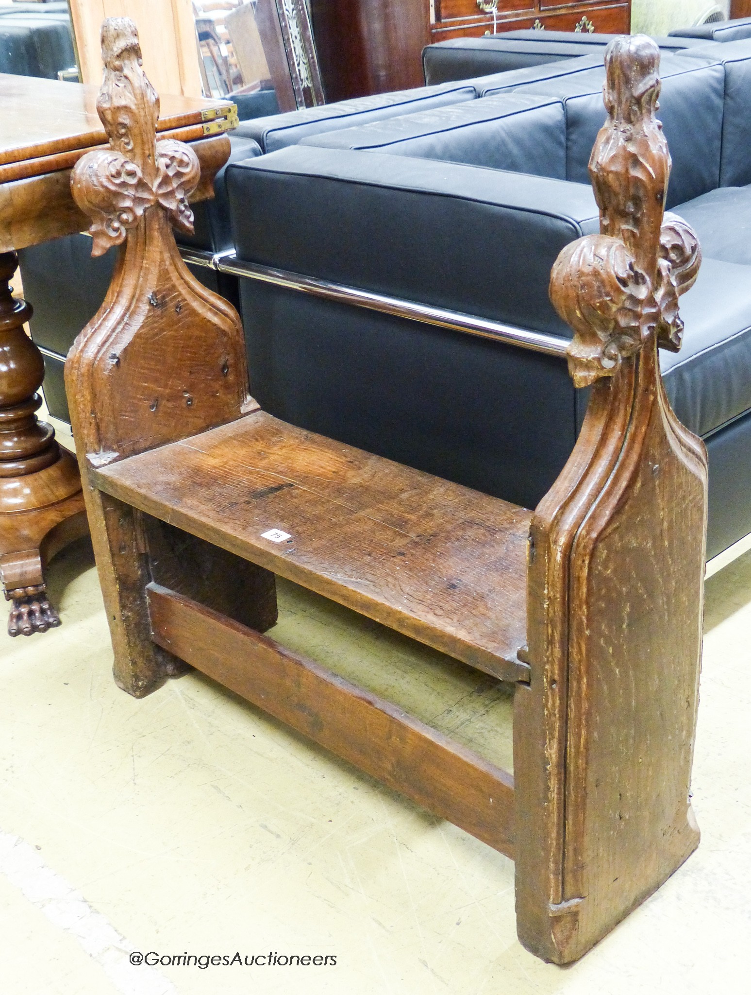 A pair of 15th century oak pew ends with stylised leaf and berry fleur-de-lys finials, joined by a later bench seat, length 85cm, depth 27cm, height 92cm